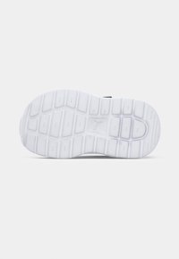 Semelle de chaussure en caoutchouc blanc avec un motif texturé, incluant des rainures proéminentes et une empreinte de logo, conçue pour l'adhérence et la durabilité.