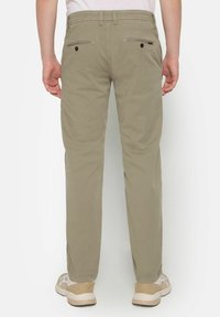 Khaki chinos with a straight-leg design, made of smooth fabric, featuring back pockets and subtle stitching details. Worn with light sneakers.