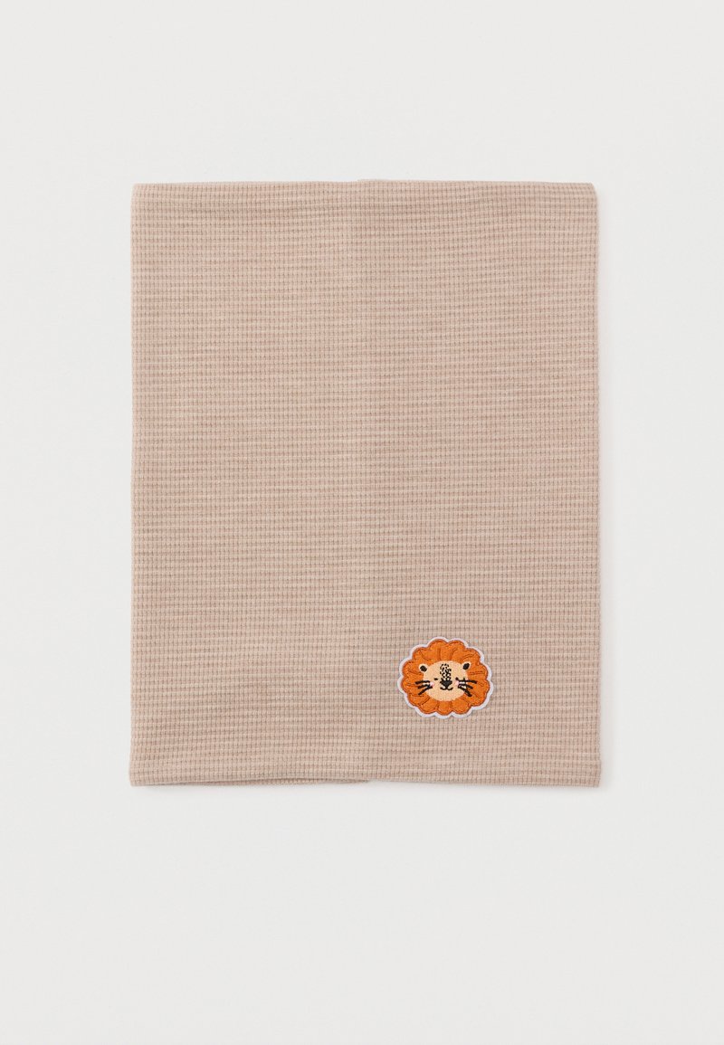 Τετράγωνο ύφασμα από μπεζ πλεκτό βεφέ με μικρό κεντημένο πορτοκαλί πρόσωπο λιονταριού κοντά στη κάτω δεξιά γωνία.