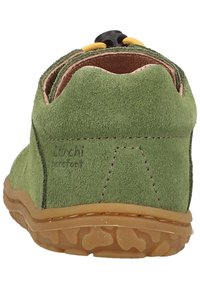 Vihreä mokkanahkakenkä pyöreällä korolla, kumipohjalla ja keltaisilla elastisilla nauhoilla. Sisältää vähäistä ommelta ja pehmeän sisävuoren.