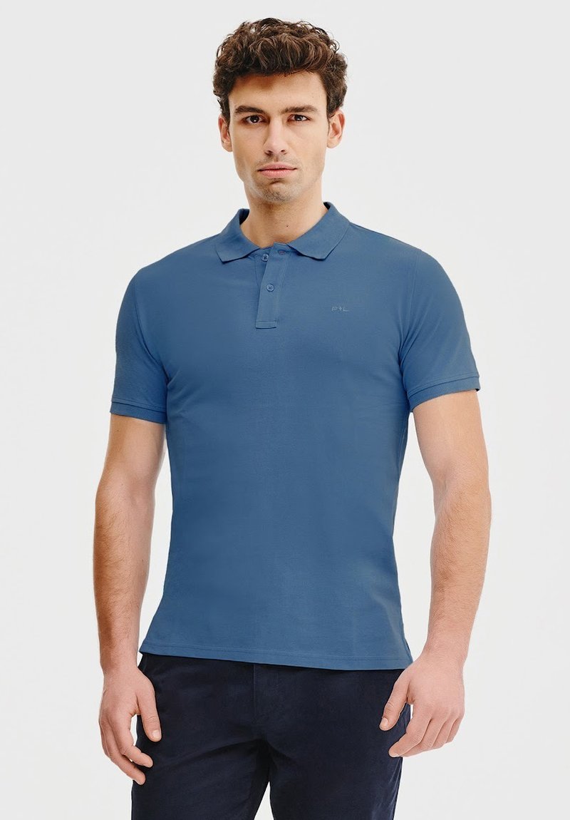 Koszulka polo w jednolitym niebieskim kolorze z bawełny, z klasycznym kołnierzykiem, krótkimi rękawami, zapięciem na dwa guziki oraz subtelnym logo na piersi.