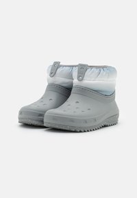 Botas de borracha cinzas com uma superfície externa texturizada, um topo em tecido franzido em azul claro e um padrão na sola para maior tração.