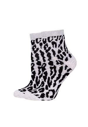 Een paar enkellange sokken met een zwart-wit luipaardprintpatroon op een lichtgrijze achtergrond.