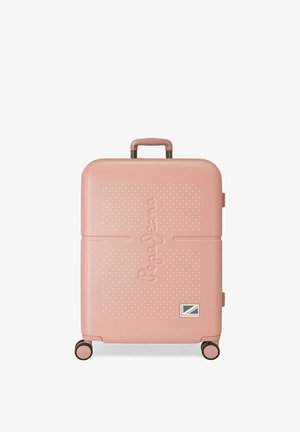 Maleta rígida de color rosa claro con cuatro ruedas, una asa superior y el nombre de la marca en relieve en el frente, de pie sobre un fondo blanco.