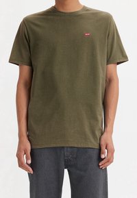 Oliwkowa bawełniana koszulka z krótkim rękawem i okrągłym dekoltem. Z przodu znajduje się małe czerwone logo Levi's umieszczone na środku klatki piersiowej.