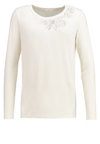 Långärmad, krämfärgad topp med rund halsringning. Har blommig spetsdetalj på ena axeln. Tillverkad av mjukt, glatt tyg.