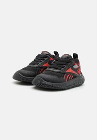 Zapatillas deportivas negras con detalles rojos; parte superior de malla, suela de goma y diseño con cordones. Presenta patrones texturizados y detalles del logo.