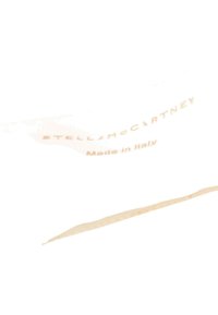 Gros plan d'une semelle blanche avec un texte beige indiquant "STELLA MCCARTNEY" et "Made in Italy" sur un fond clair.