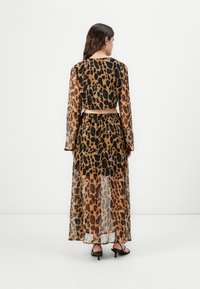 Maxi haljina s leopard printom, dugim rukavima, prozirnom tkaninom i uskim strukom. Ima crno-smeđu šaru i lepršavi kroj.