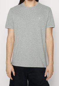 T-shirt grigio a maniche corte realizzato in tessuto morbido, con collo rotondo e un piccolo logo ricamato "II" sul petto.