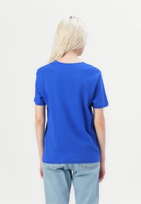 Blå bomull t-skjorte med korte ermer og rund hals, med en glatt tekstur og en tettsittende fasong, båret med lyseblå jeans.