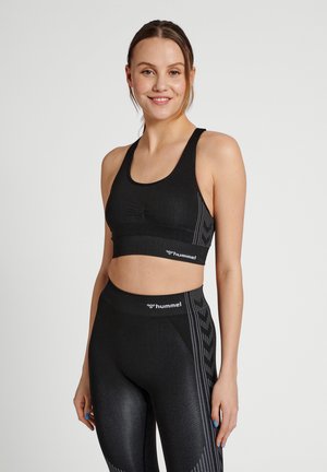 Zwarte sportbeha met een gestructureerde afwerking, met een racerback ontwerp. Gepaard met hoge taille leggings die een reflecterend zijpatroon tonen.