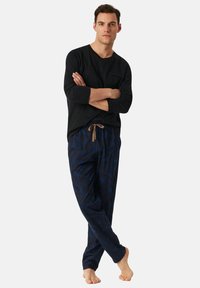 Černá košile s dlouhým rukávem v kombinaci s tmavě modrými vzorovanými pyžamovými kalhotami s mašlí v pase a texturovaným motivem listů.