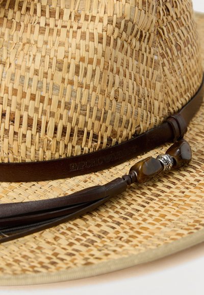 Chapeau fedora en paille tressée avec bande en cuir marron foncé et pampille ornée de perles décoratives sur le bord.