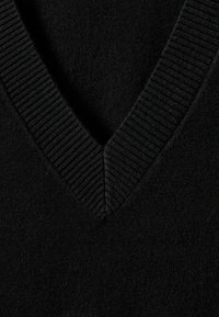 Melna džemperis ar V-veida kakla dizainu, teksturētu ribinātu apkakli un mīkstu apdari. Audums izskatās biezs un ērts, piemērots vairākām kārtām.