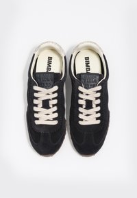 Zapatillas de ante negras con cordones beige, que cuentan con una suela de goma texturizada y un parche de cuero con logo en la lengüeta.