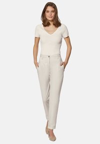 Lichtgekleurde, hoge taillebroeken met zijzakken, tapered beenontwerp en een gladde textuur, gecombineerd met een aansluitend, geribbeld wit topje.