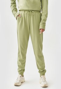 Lichtgroene sweatpants gemaakt van zachte stof, met een elastische tailleband met trekkoord, zijzakken en taps toelopende boorden.