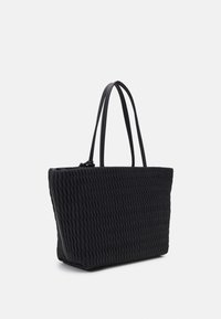 Sac fourre-tout noir en tissage avec longues anses, présentant une surface texturée et une forme rectangulaire spacieuse. Pas de quincaillerie ni d'accents visibles.