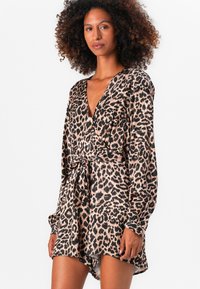Robe portefeuille à imprimé léopard avec manches longues, décolleté en V profond, taille ceinturée et ourlet asymétrique, en tissu doux et léger.