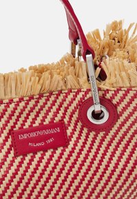 Czerwona i beżowa torebka w tkanym stylu z frędzlami na górnej krawędzi, czerwonymi skórzanymi akcentami, srebrnymi elementami metalowymi oraz metką Emporio Armani Milano 1981.