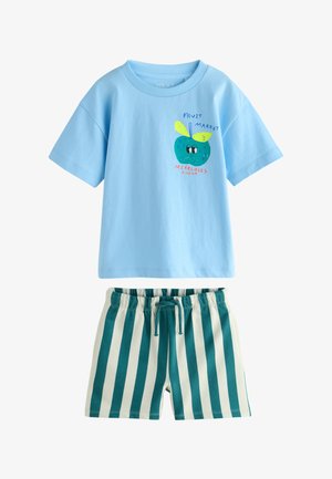 Lyseblå t-shirt med korte ærmer med en tegneserieagtig grøn frugt og tekst, kombineret med hvide shorts med lodrette mørkeblågrønne striber og snøre i taljen.