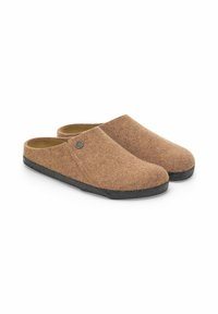 Zoccoli in feltro marrone con design arrotondato, suole in gomma nera e un piccolo accento metallico sul lato superiore. Casual e facili da indossare.