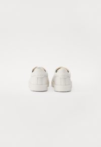 Baskets en cuir blanc à texture lisse, design basse, avec un talon arrondi. Présentent un motif de couture simple et une semelle intérieure rembourrée.