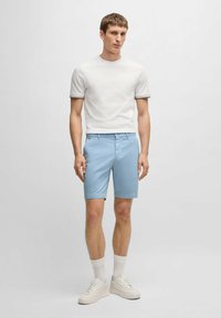 Vit t-shirt med rund halsringning och kontrasterande randig kant, ihop med ljusblå shorts och vita sneakers. Slät bomullstyg, normal passform.
