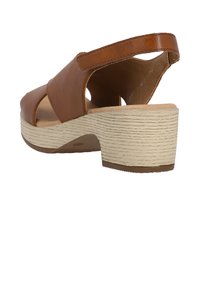 Brown leather sandal with open toe, adjustable back strap, and a textured beige wedge heel. Features a smooth upper and cushioned insole.