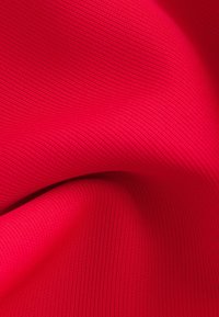 Gros plan sur un tissu côtelé rouge vif montrant la texture et les plis.