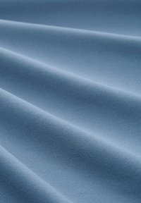 Lichtblauwe stof met een gladde textuur, met zachte golven en subtiele glans, ideaal voor bekleding of kleding.