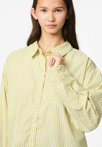 Geel gestreepte button-up overhemd met een kraag, voorzien van verticale blauwe strepen en een zak. Lange mouwen met knoopmanchetten.