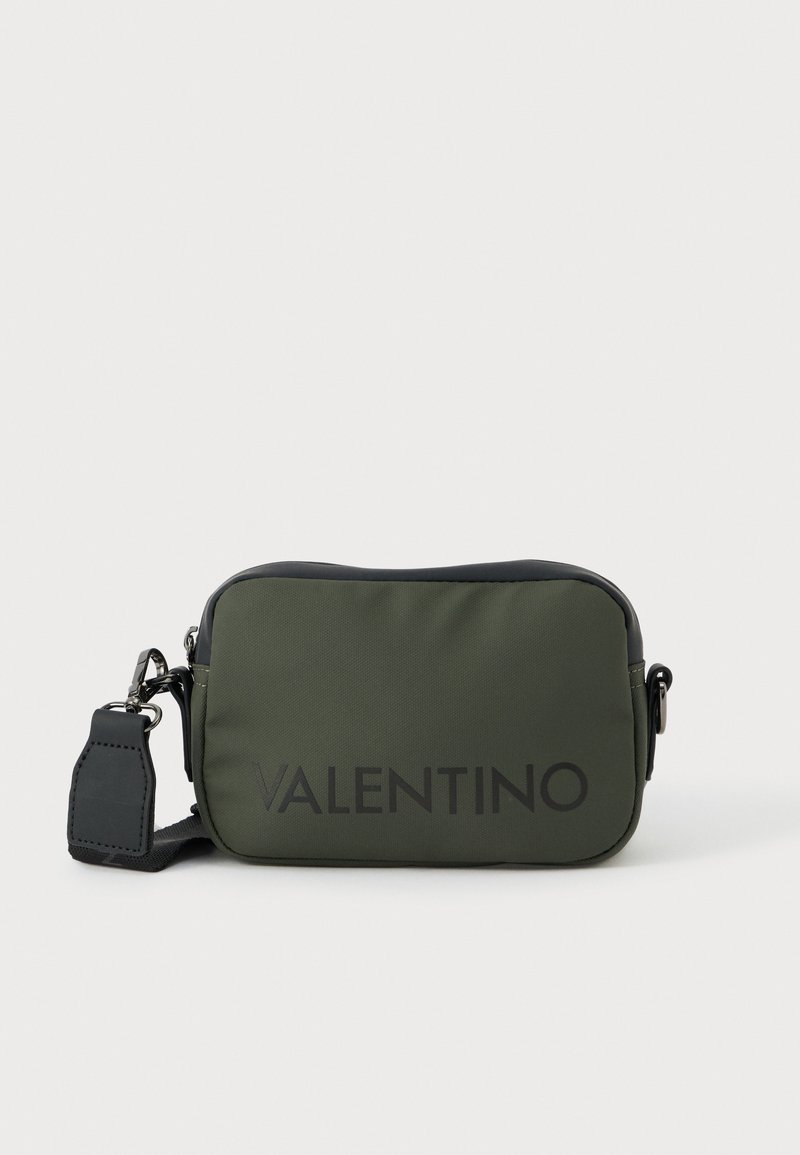Ορθογώνια τσάντα μέσης σε ελιά πράσινο χρώμα με μαύρες λεπτομέρειες και ρυθμιζόμενο λουρί, με μεγάλο μαύρο λογότυπο Valentino στο μπροστινό μέρος.