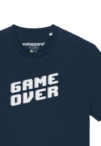 T-shirt en coton bleu marine avec un col rond, arborant le texte pixelisé blanc "GAME OVER" affiché en grand sur la poitrine.