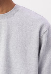 Sweat-shirt gris à col rond, fabriqué en mélange de coton doux. Caractérisé par une texture subtile et une coupe décontractée.