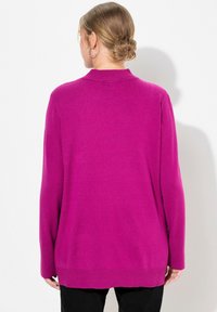 Fuchsiový pletený sveter s voľným strihom, dlhými rukávmi a ribbovaným lemom. Mäkká textúra, stredná dĺžka a minimálne detaily.