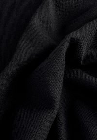 Tissu tricoté noir à la texture douce, présentant un motif discret et étroitement tissé. Le matériau semble élastique et lisse.