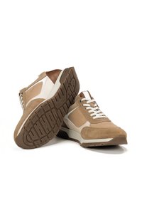 Scarpe da allenamento color sabbia e crema con una combinazione di suede e mesh sulla tomaia, caratterizzate da un accento in pelle marrone e una suola in gomma con motivi antiscivolo.