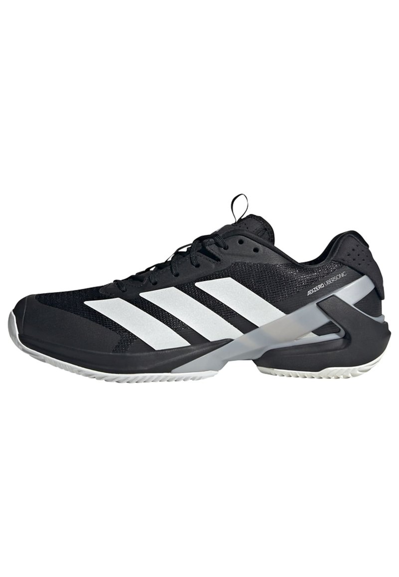 Czarne buty sportowe z siateczkową cholewką, białym wzorem w trzy paski, grubą podeszwą i gumowym wzorem zapewniającym przyczepność. Posiadają wzmocniony obcas i sznurówki.
