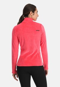 Rosa Fleece-Jacke mit hohem Kragen, die eine glatte Textur und eine taillierte Passform aufweist, verziert mit einem kleinen schwarzen Logo auf dem oberen Rücken.
