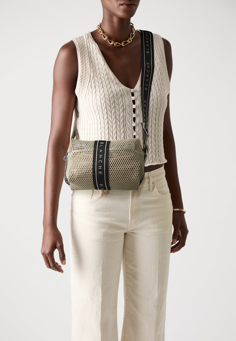 Borsa in maglia beige con dettaglio nero e testo "BLANCHE". Forma rettangolare compatta con chiusura a zip superiore.