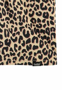 Le tissu en impression léopard présente des motifs noirs et bruns sur fond caramel. L'étiquette "Pockies" est visible dans le coin inférieur. Texture lisse.