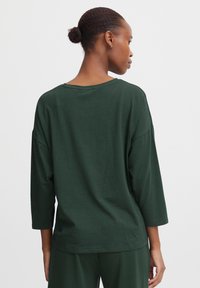 Donkergroene, ontspannen pasvorm top met driekwartmouwen, zachte stoftextuur en brede halslijn, met een eenvoudig, strak design.