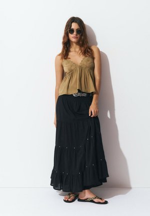 Olive green, v-neck, flared blouse paired with a black tiered maxi skirt featuring silver accents. Worn with leopard print flip-flops.