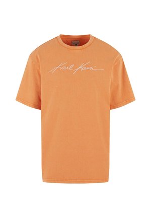 Oranž lühikeste varrukatega T-särk, millel on valge "Karl Kani" allkirjalogo rinnal keskel, ümara kaelakaare ja mugava lõikega.