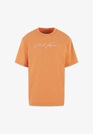 Oranžové tričko s krátkym rukávom a bielym podpisom loga "Karl Kani" uprostred na hrudi, s okrúhlym výstrihom a voľným strihom.