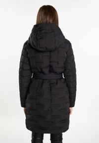 Geacă puffer neagră cu glugă, având un talie cu curea, textură matlasată și design până la genunchi. Material neted cu detalii de cusătură subtile.