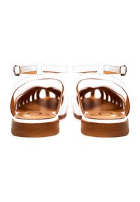 Paire de sandales plates blanches à brides avec semelles marron vues de dos, avec des brides à la cheville et de petites boucles métalliques.