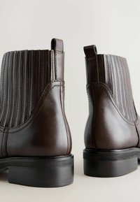 Bottines en cuir marron avec un design à cannelures verticales, dotées d'un bout rond, de tirettes et d'un talon empilé noir.